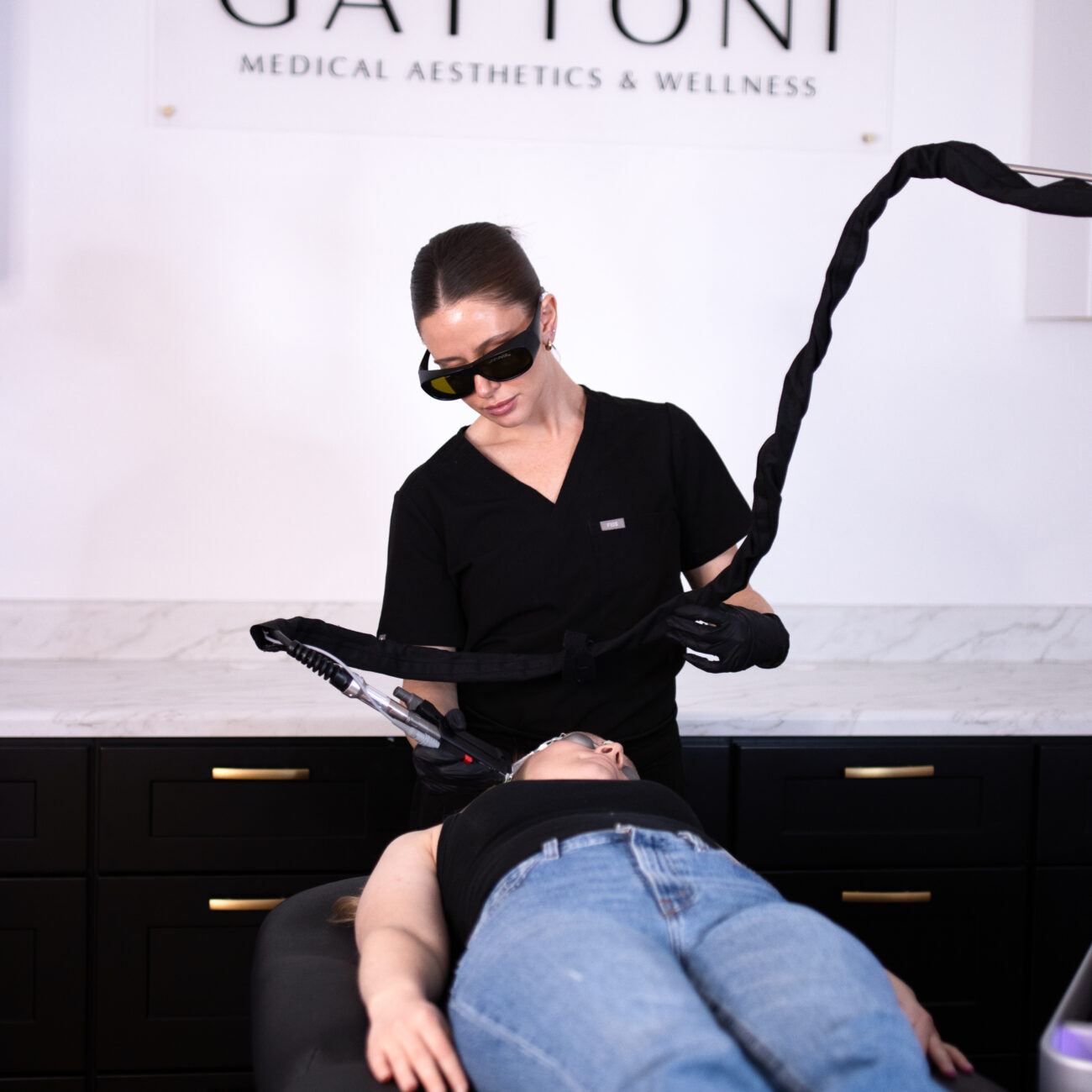 A female nurse using a laser for laser hair removal on a female patient that is lying down